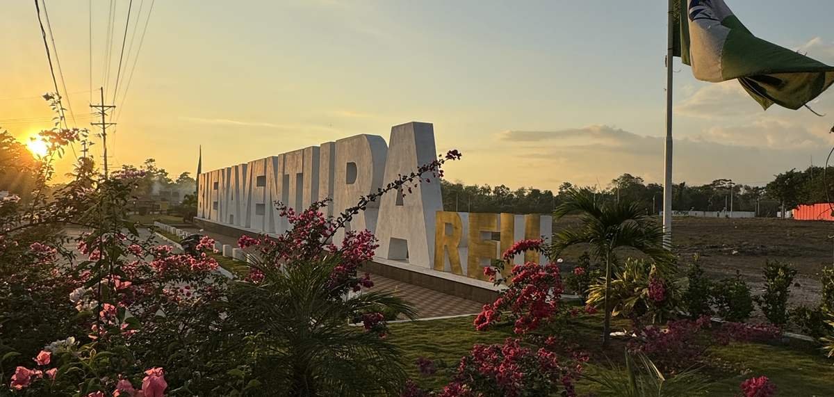 Letras monumentales de Buenaventura al atardecer, entre bugambilias