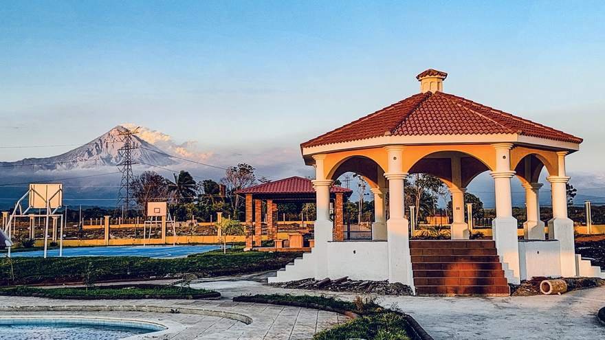 Kiosco, rancho y canchas de un proyecto entregado, con un volcán al fondo