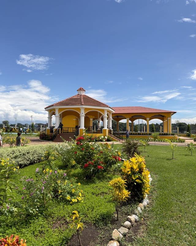 Ranchón y gazebo amarillos rodeados de jardines florecidos en Palmeras Sur, un proyecto ya entregado