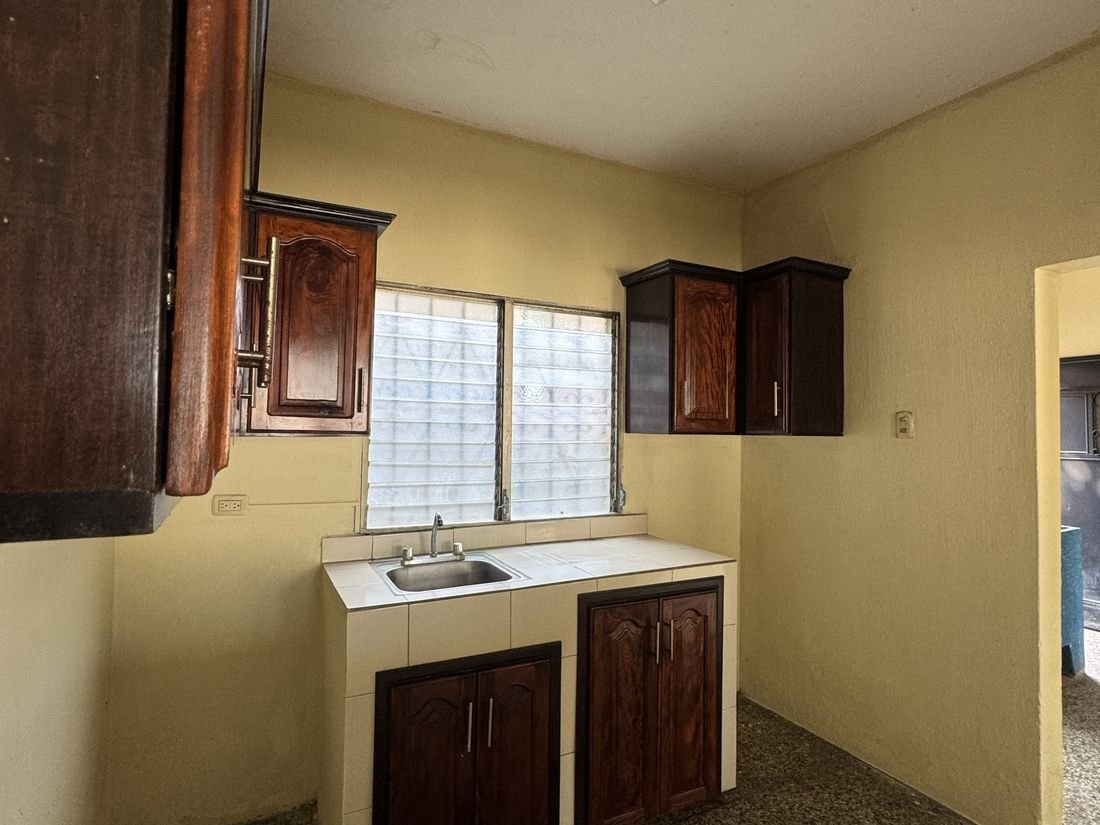Área de cocina con gabinetes de madera y poyo de azulejo