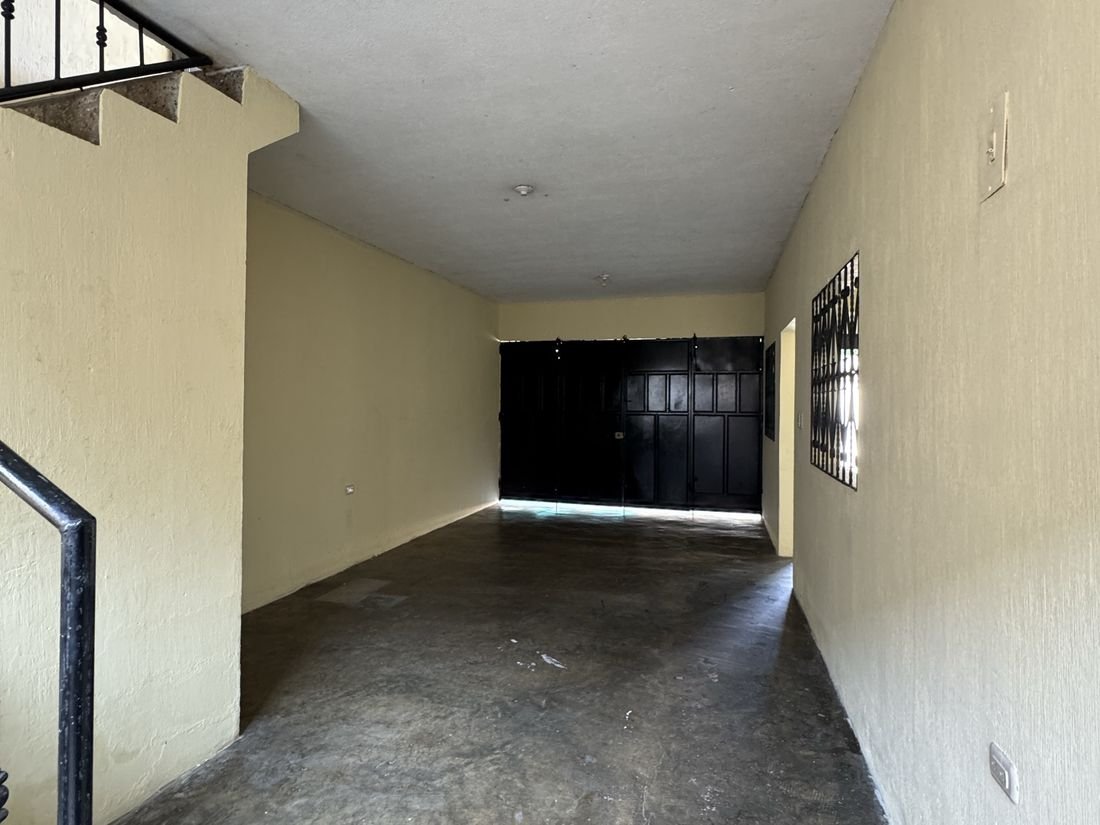 Garaje amplio del primer nivel, con portón de metal hacia la calle