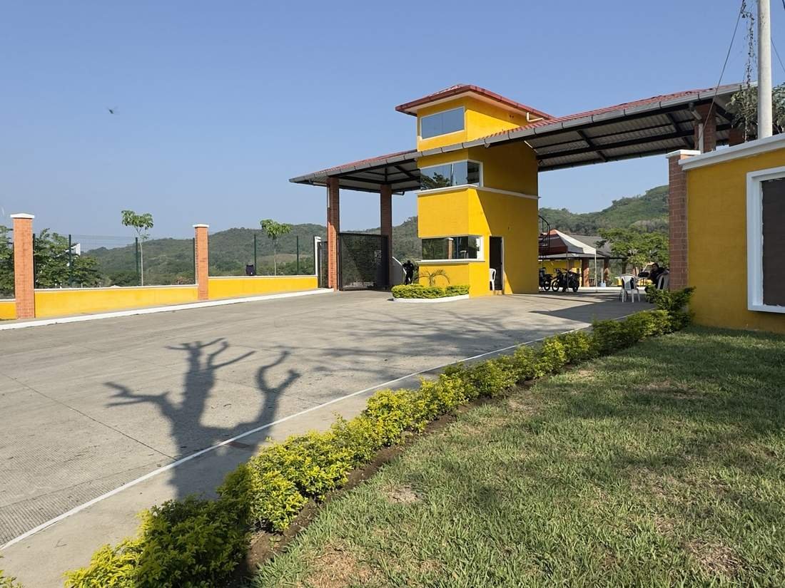 Ingreso interior de Buenaventura San Alberto, con calle pavimentada y muro perimetral