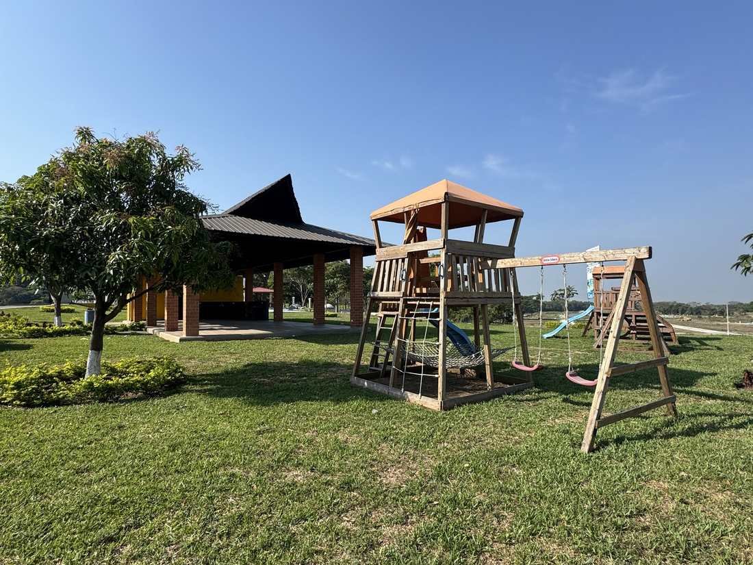 Áreas verdes con juegos infantiles y el salón de Buenaventura San Alberto