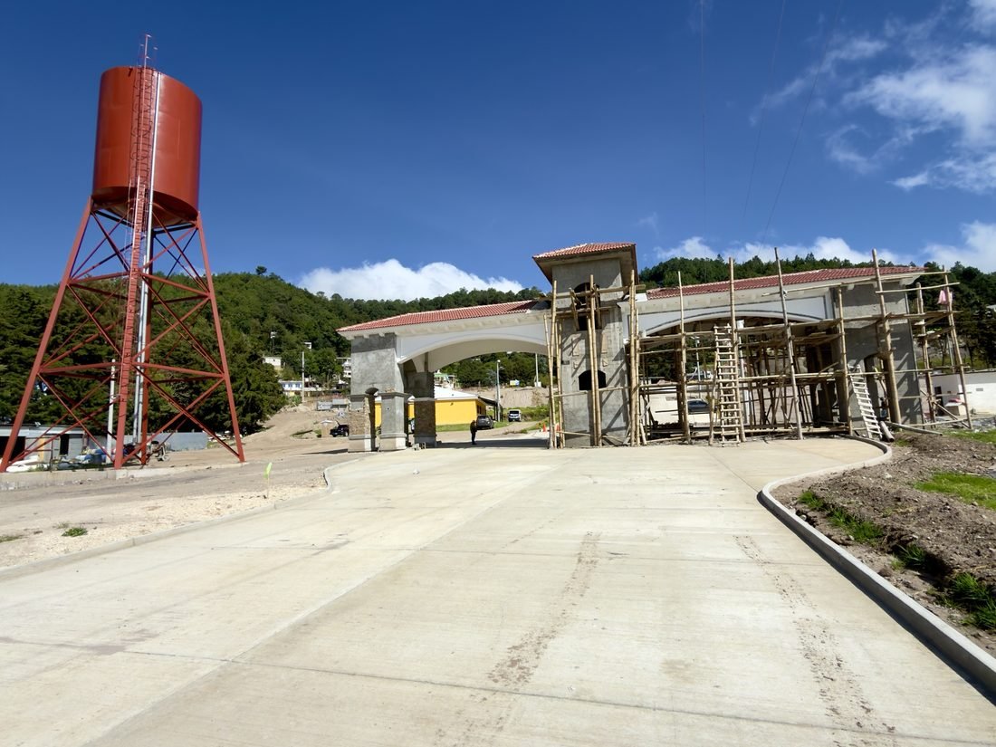 La garita de ingreso de Buenaventura Tecpán en construcción, con andamios y el tanque de agua del proyecto